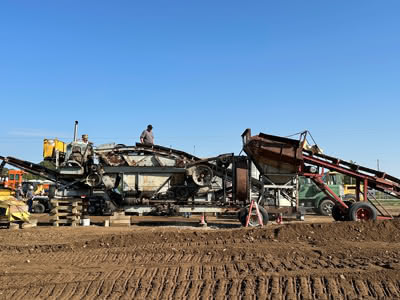 A machine in front of dirt against a blue sky